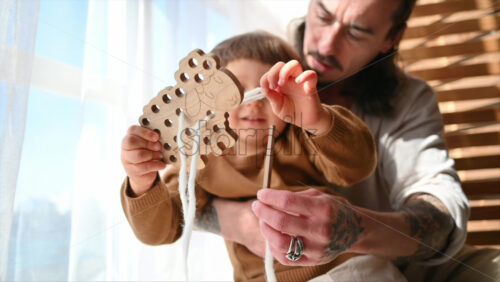 Video - Father playing with his son with ecological wooden toys near the window