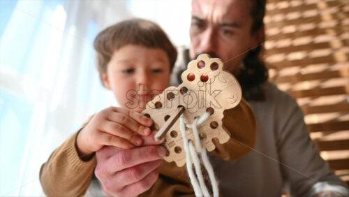 Video - Father playing with his son with ecological wooden toys near the window