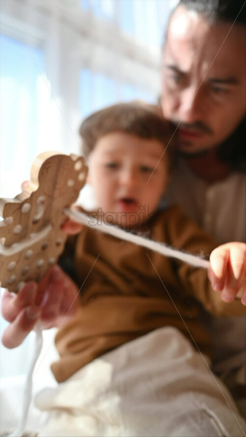 Video - Father playing with his son with ecological wooden toys near the window. Vertical