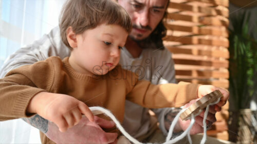Video - Father playing with his son with ecological wooden toys near the window