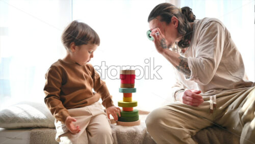 Video - Father playing with his son with colourful, ecological wooden toys near a window