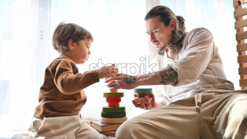Video - Father playing with his son with colourful, ecological wooden toys near a window