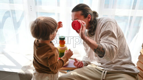 Video - Father playing with his son with colourful, ecological wooden toys near a window