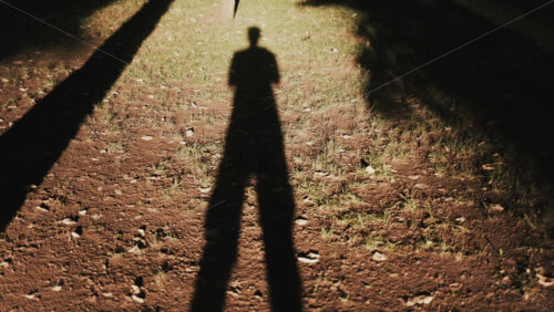 Video - Long human shadow stretching on earthy ground during golden hour