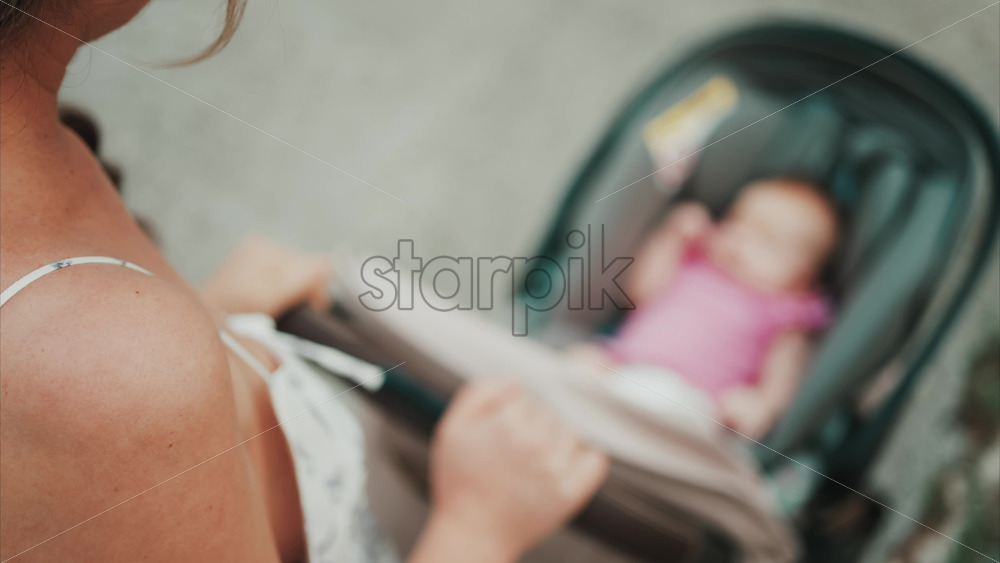 Video - Woman in floral dress pushing a baby stroller outdoors