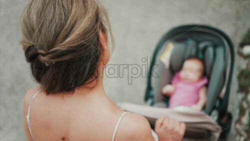 Video - Woman in floral dress pushing a baby stroller outdoors