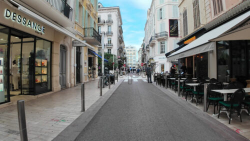 Video - Cannes, France - September 20, 2025: Charming narrow street with outdoor restaurants, boutique shops, and Vespas parked, capturing the Mediterranean vibe