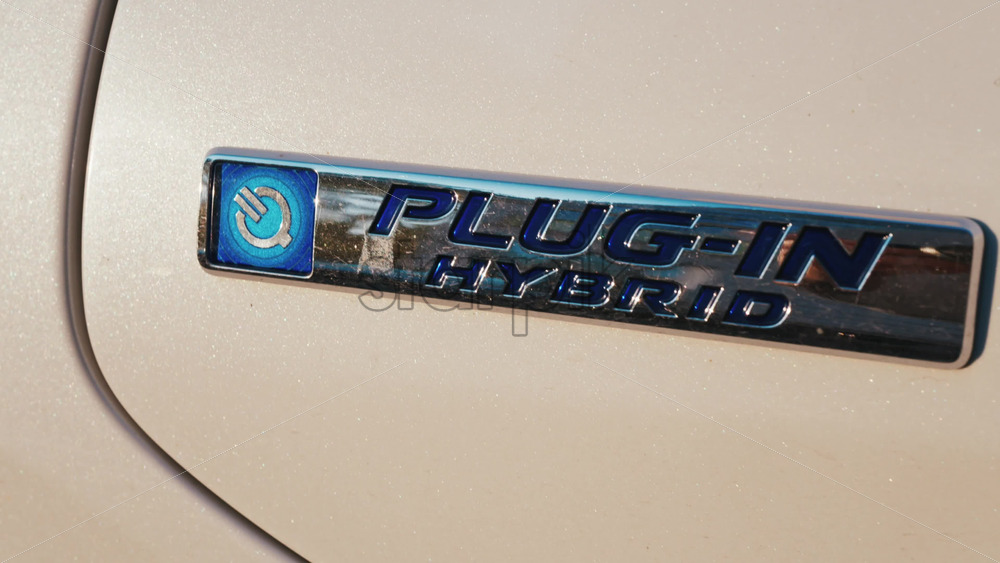 Video - Shining close up of a plug in hybrid badge on a car under sunlight
