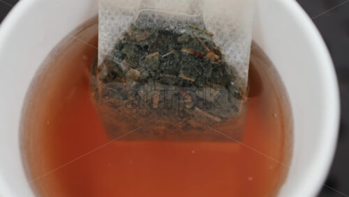 Video - Close up of a tea bag steeping in hot water, releasing rich colour and aroma