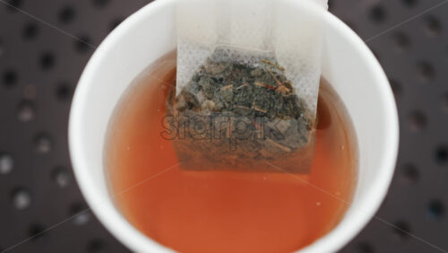 Video - Close up of a tea bag steeping in hot water, releasing rich colour and aroma
