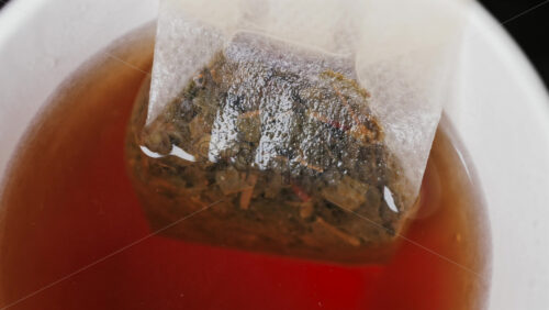 Video - Close up of a tea bag steeping in hot water, releasing rich colour and aroma