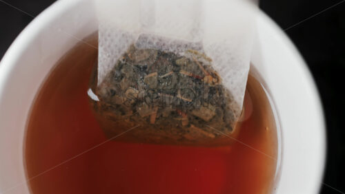 Video - Close up of a tea bag steeping in hot water, releasing rich colour and aroma