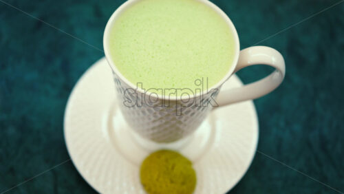 Video - Close up of a smooth matcha latte with vibrant green foam in a white cup