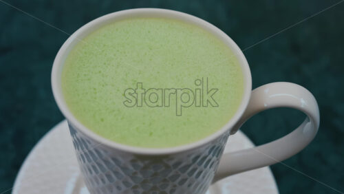 Video - Close up of a smooth matcha latte with vibrant green foam in a white cup