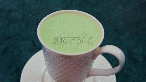 Video - Close up of a smooth matcha latte with vibrant green foam in a white cup