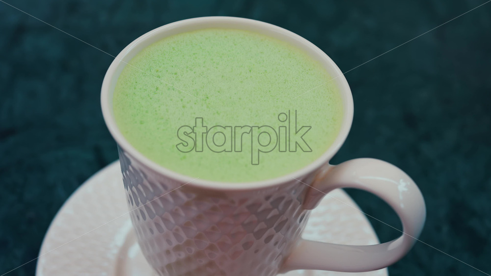 Video - Close up of a smooth matcha latte with vibrant green foam in a white cup