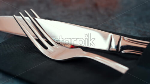 Video - Close up of silver cutlery placed neatly on a dark napkin at a restaurant