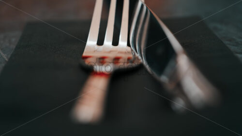 Video - Close up of silver cutlery placed neatly on a dark napkin at a restaurant