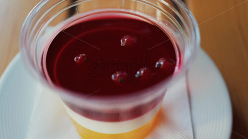 Video - Close up of a bright layered jelly dessert in a clear cup on a wooden table