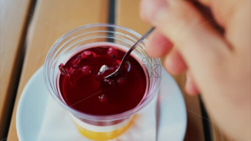 Video - Close up of a bright layered jelly dessert in a clear cup on a wooden table
