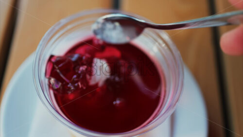 Video - Close up of a bright layered jelly dessert in a clear cup on a wooden table