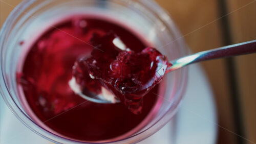 Video - Close up of a spoon breaking into vibrant red jelly dessert
