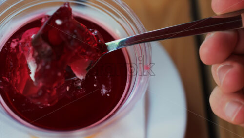 Video - Close up of a spoon breaking into vibrant red jelly dessert