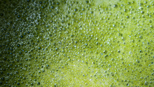 Video - Close up of a smooth matcha latte with vibrant green foam in a white cup