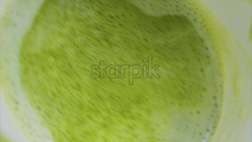 Video - Close up of a smooth matcha latte with vibrant green foam in a white cup