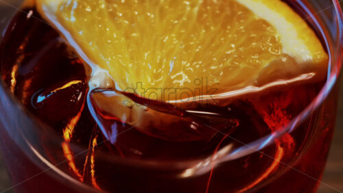 Video - Close up of a Negroni cocktail with orange slice and ice cubes on a wooden table