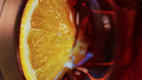 Video - Close up of a Negroni cocktail with orange slice and ice cubes on a wooden table