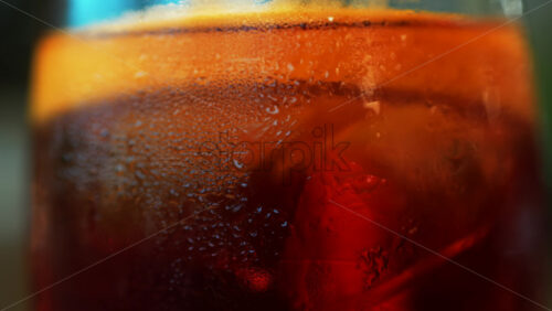 Video - Close up of a Negroni cocktail with orange slice and ice cubes on a wooden table