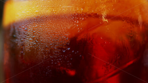 Video - Close up of a Negroni cocktail with orange slice and ice cubes on a wooden table