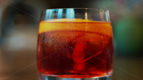 Video - Close up of a Negroni cocktail with orange slice and ice cubes on a wooden table
