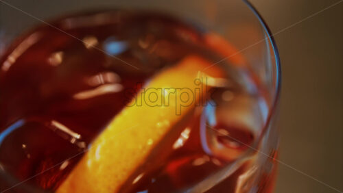 Video - Close up of a Negroni cocktail with orange slice and ice cubes on a wooden table
