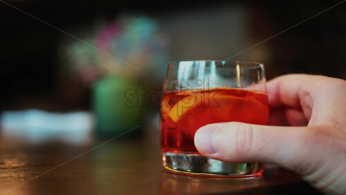 Video - Man's hand holding a glass of Negroni cocktail on a bar counter