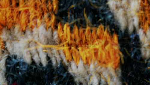 Video - Close up view of woven wool fibers in warm yellow and black tones