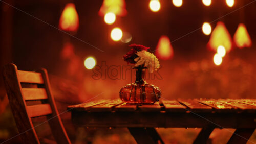 Video - A wooden table with flowers illuminated by soft hanging lights