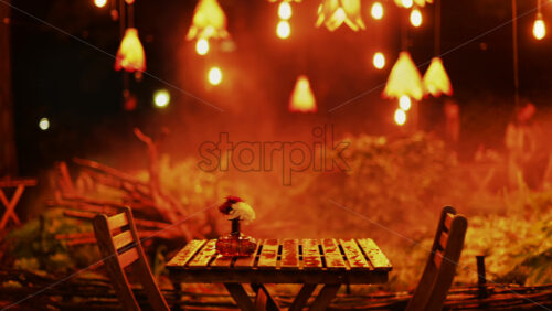 Video - A wooden table with flowers illuminated by soft hanging lights