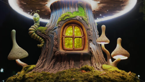 Video - A miniature fantasy tree house with glowing windows, mushrooms, and a smiling caterpillar figure