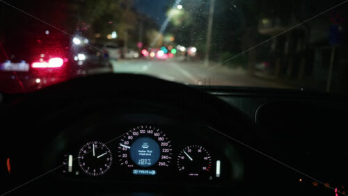 Video - Out of focus city lights seen through a car windshield at night, with the steering wheel in foreground
