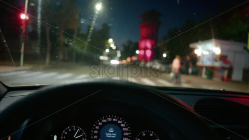 Video - Blurred view of city intersection at night, seen through a car windshield with red traffic lights glowing