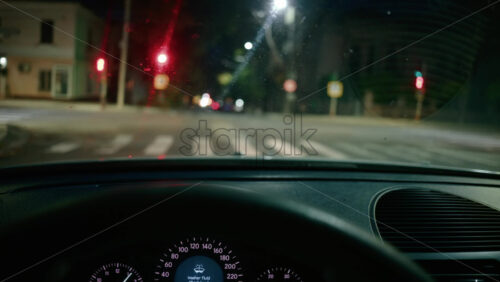 Video - Blurred view of city intersection at night, seen through a car windshield with red traffic lights glowing