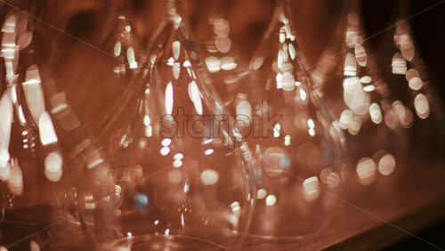 Video - Close up view of multiple glass vessels softly illuminated with warm light that creates a golden bokeh effect in the background