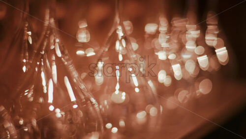 Video - Close up view of multiple glass vessels softly illuminated with warm light that creates a golden bokeh effect in the background