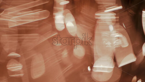 Video - Close up view of multiple glass vessels softly illuminated with warm light that creates a golden bokeh effect in the background