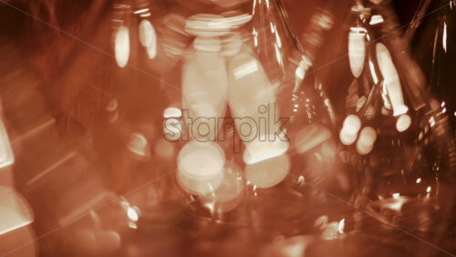 Video - Close up view of multiple glass vessels softly illuminated with warm light that creates a golden bokeh effect in the background