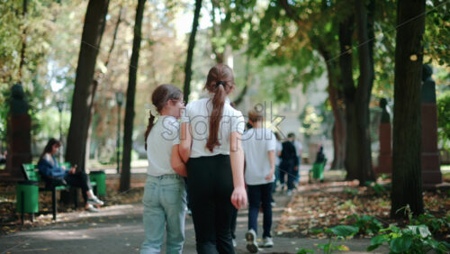 Video - Chisinau, Moldova - September 25, 2025: Group of school children strolling under green trees in a sunny park