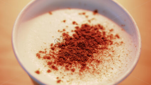 Video - Close up of cocoa sprinkled over frothy milk, with rich warm tones