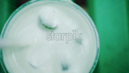 Video - Close up of a white liquid being stirred in a glass with ice